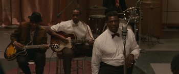 Two men in white shirts and bow ties are playing guitar and singing