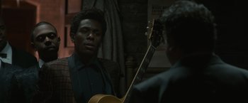 A man standing next to another man holding a guitar