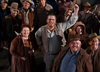 Movie still from “Calamity Jane” (1953), directed by David Butler – A group of people standing around each other; Medium shot, High angle