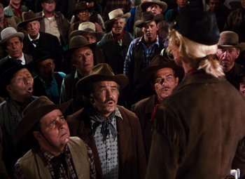 Movie still from “Calamity Jane” (1953), directed by David Butler – A group of men in hats and jackets standing in front of a crowd; Medium shot, High angle