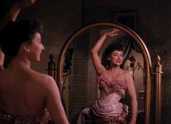 Movie still from “Calamity Jane” (1953), directed by David Butler – A woman in a pink and gold dress in a mirror; Medium shot, Over the shoulder angle