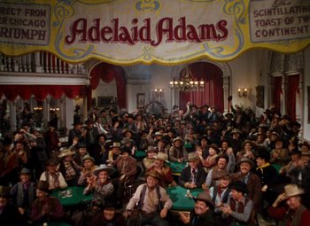 Movie still from “Calamity Jane” (1953), directed by David Butler – A large group of men sitting around a table; Extreme Wide shot, High angle