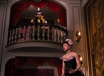 Movie still from “Calamity Jane” (1953), directed by David Butler – A man and a woman are standing in front of a balcony; Wide shot, Low angle