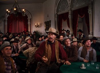 Movie still from “Calamity Jane” (1953), directed by David Butler – A group of men sitting in a room with hats on; Wide shot, High angle