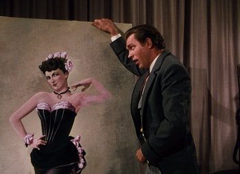 Movie still from “Calamity Jane” (1953), directed by David Butler – A man standing next to a painting of a woman; Medium shot, Low angle