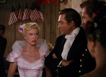 Movie still from “Calamity Jane” (1953), directed by David Butler – A man and a woman standing next to each other in a room; Medium shot, Over the shoulder angle