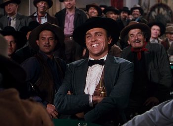 Movie still from “Calamity Jane” (1953), directed by David Butler – A group of men wearing hats and smiling for the camera; Medium shot, Low angle