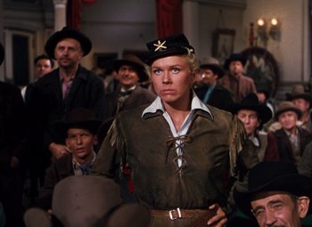 Movie still from “Calamity Jane” (1953), directed by David Butler – A man in a cowboy hat standing in front of a group of men; Medium shot, Low angle