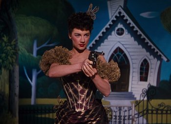Movie still from “Calamity Jane” (1953), directed by David Butler – A woman holding a gun while standing in front of a building; Medium shot, Low angle