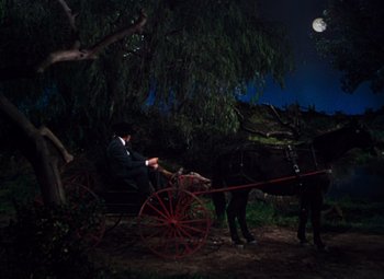 Movie still from “Calamity Jane” (1953), directed by David Butler – A man riding a horse drawn carriage at night; Wide shot, High angle