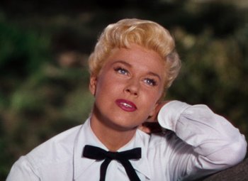 Movie still from “Calamity Jane” (1953), directed by David Butler – A woman with blonde hair wearing a white shirt and black bow tie; Close Up shot, Low angle