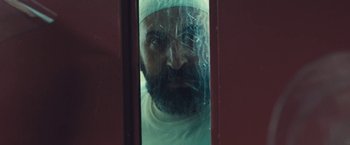 Movie still from “Camp X-Ray” (2014), directed by Peter Sattler – A man with a beard wearing a white hat; Close Up shot, Over the shoulder angle