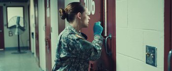 Movie still from “Camp X-Ray” (2014), directed by Peter Sattler – A woman in fatigues opening a door to a building; Medium shot, Over the shoulder angle