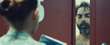 Movie still from “Camp X-Ray” (2014), directed by Peter Sattler – A man is looking at a cat through a fence; Close Up shot, Over the shoulder angle