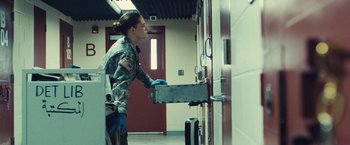 Movie still from “Camp X-Ray” (2014), directed by Peter Sattler – A woman in a military uniform holding a metal object; Medium shot, Low angle