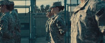 Movie still from “Camp X-Ray” (2014), directed by Peter Sattler – Two soldiers standing next to each other in front of a chain link fence; Medium shot, Low angle