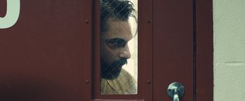 Movie still from “Camp X-Ray” (2014), directed by Peter Sattler – A man with a beard looking through a fence; Close Up shot, Over the shoulder angle