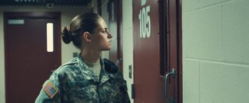 Movie still from “Camp X-Ray” (2014), directed by Peter Sattler – A woman in a military uniform standing in front of a door; Medium shot, Over the shoulder angle