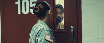 Movie still from “Camp X-Ray” (2014), directed by Peter Sattler – A woman in a military uniform looking at a man in a prison uniform; Medium shot, Over the shoulder angle