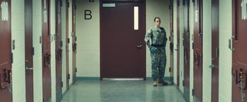 Movie still from “Camp X-Ray” (2014), directed by Peter Sattler – A soldier standing in front of a red door; Wide shot, Low angle