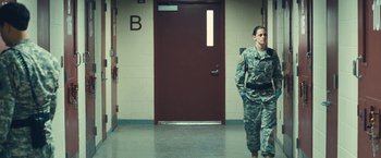 Movie still from “Camp X-Ray” (2014), directed by Peter Sattler – A woman in uniform walking in front of a door; Wide shot, Low angle