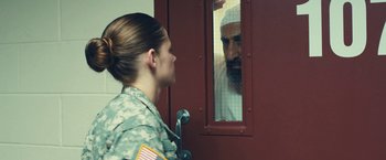 Movie still from “Camp X-Ray” (2014), directed by Peter Sattler – A woman in a military uniform looking at a man in a white shirt; Medium shot, Over the shoulder angle