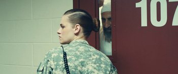 Movie still from “Camp X-Ray” (2014), directed by Peter Sattler – A woman in a military fatigues looking out a window; Medium shot, Over the shoulder angle