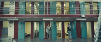 Movie still from “Camp X-Ray” (2014), directed by Peter Sattler – Two men standing in front of a jail cell; Wide shot, High angle