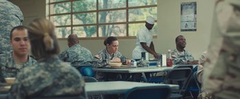 Movie still from “Camp X-Ray” (2014), directed by Peter Sattler – A woman in a military uniform eating at a table; Wide shot, Over the shoulder angle