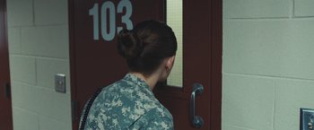 Movie still from “Camp X-Ray” (2014), directed by Peter Sattler – A woman in fatigues looking out of a door; Close Up shot, Over the shoulder angle