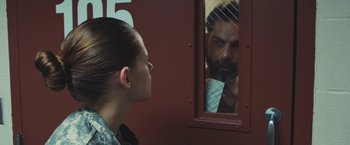 Movie still from “Camp X-Ray” (2014), directed by Peter Sattler – A woman looking at a man through a window; Medium shot, Over the shoulder angle