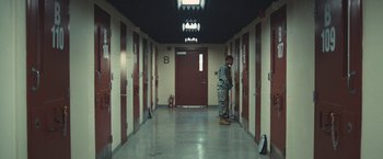 Movie still from “Camp X-Ray” (2014), directed by Peter Sattler – A man standing in the hallway of a jail cell; Wide shot, High angle
