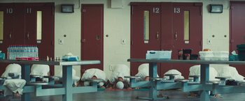 Movie still from “Camp X-Ray” (2014), directed by Peter Sattler – A group of men in white shirts kneeling on the ground; Extreme Wide shot, High angle