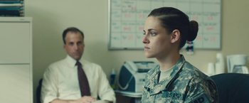 Movie still from “Camp X-Ray” (2014), directed by Peter Sattler – A woman in a uniform sitting in front of a man; Medium shot, Over the shoulder angle