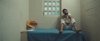 Movie still from “Camp X-Ray” (2014), directed by Peter Sattler – A man sitting on a bed in a jail cell; Medium shot, High angle