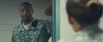 Movie still from “Camp X-Ray” (2014), directed by Peter Sattler – A man in a military fatigues standing in front of a door; Medium shot, Over the shoulder angle