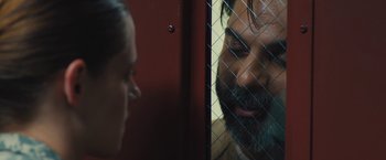 Movie still from “Camp X-Ray” (2014), directed by Peter Sattler – A man and a woman looking at each other through a chain link fence; Close Up shot, Over the shoulder angle