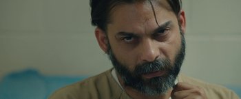 Movie still from “Camp X-Ray” (2014), directed by Peter Sattler – A person with a beard; Close Up shot, Over the shoulder angle