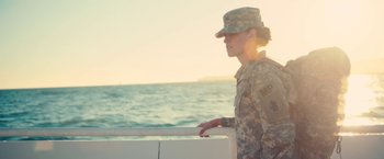 Movie still from “Camp X-Ray” (2014), directed by Peter Sattler – A woman in a military uniform standing next to a body of water; Medium shot, Low angle