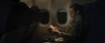 Movie still from “Camp X-Ray” (2014), directed by Peter Sattler – A soldier is reading a book on a plane; Medium shot, High angle