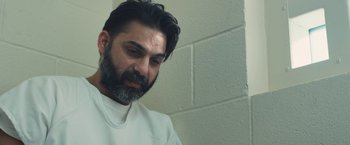 Movie still from “Camp X-Ray” (2014), directed by Peter Sattler – A man with a gray beard is looking down; Close Up shot, Low angle