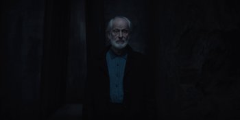 Movie still from “Dark” (2017), created by Baran bo Odar – An old man with a white beard wearing a blue shirt; Medium shot, Low angle