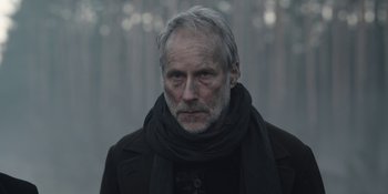 Movie still from “Dark” (2017), created by Baran bo Odar – An older man wearing a black scarf and a black jacket; Close Up shot, Low angle