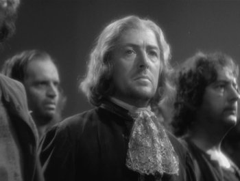 Movie still from “Captain Blood” (1935), directed by Michael Curtiz – A black and white photo of a man with long white hair; Close Up shot, Low angle