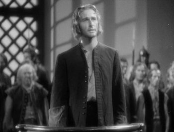Movie still from “Captain Blood” (1935), directed by Michael Curtiz – A black and white photo of a man standing in front of a group of people; Medium shot, Over the shoulder angle