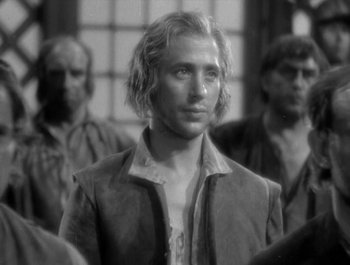 Movie still from “Captain Blood” (1935), directed by Michael Curtiz – Black and white photograph of a man in front of a group of men; Close Up shot, Over the shoulder angle