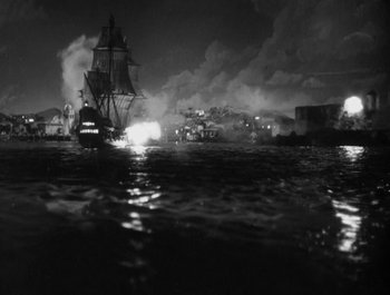 Movie still from “Captain Blood” (1935), directed by Michael Curtiz – A ship in the water at night with smoke billowing from it; Extreme Wide shot, High angle