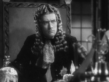 Movie still from “Captain Blood” (1935), directed by Michael Curtiz – A man in a wig sitting in front of a mirror; Close Up shot, Over the shoulder angle