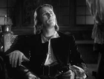 Movie still from “Captain Blood” (1935), directed by Michael Curtiz – A black and white photo of a man sitting in a chair; Close Up shot, Low angle