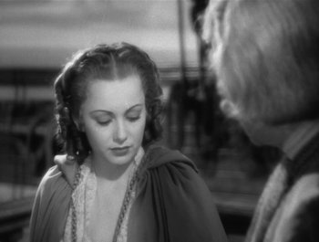 Movie still from “Captain Blood” (1935), directed by Michael Curtiz – A black - and - white photo of a young woman and an older man; Close Up shot, Over the shoulder angle